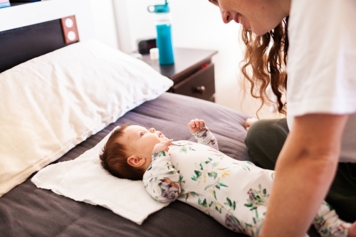 Lifestyle shot of happy mother and baby interacting together in bedroom