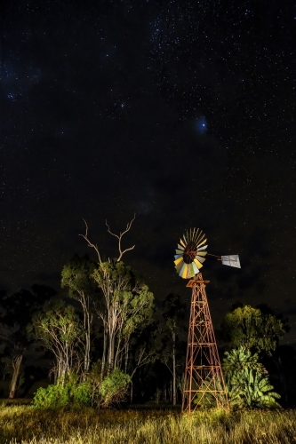 Light painting of rural windmill at night with stars.