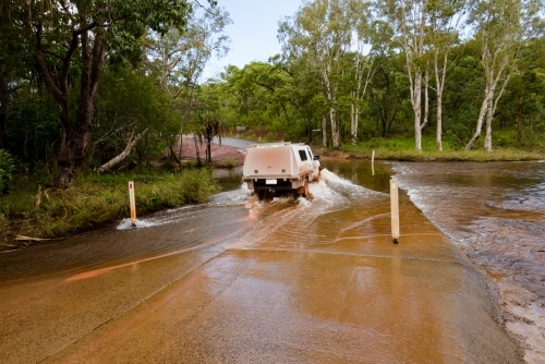 Light truck driving through flooded causeway.