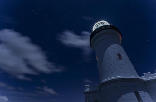 lighthouse at night with cloudy sky behind