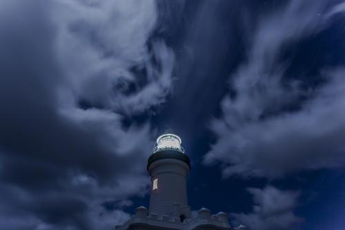 lighthouse at night with cloudy sky behind