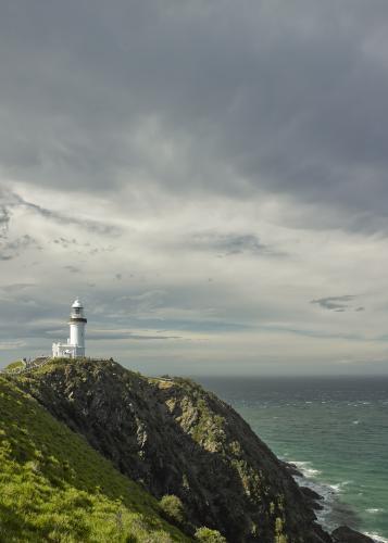 Lighthouse on headland against stormy sky