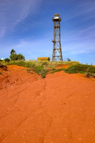 Lighthouse tower surrounded by red dirt and blue sky