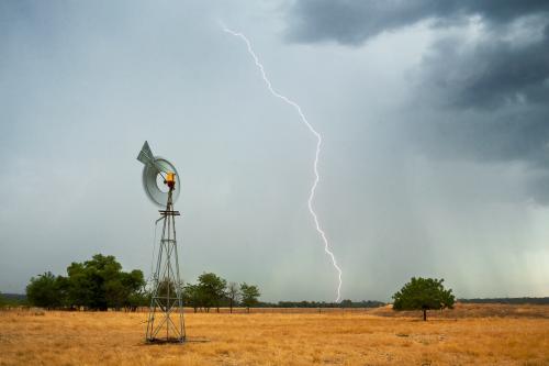 Lightning strikes ahead of a thunderstorm on farmland - Australian Stock Image