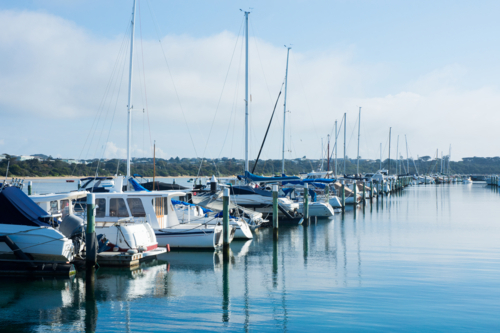 Line of boats moored in boat harbour with blue sky - Australian Stock Image