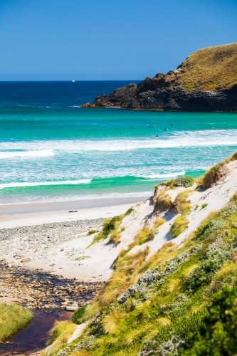 Lion Rock and distant surfers - Australian Stock Image