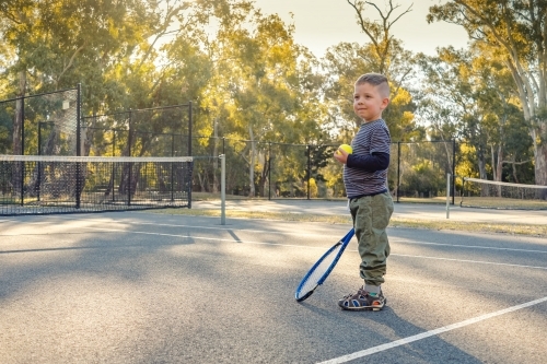 little australian boy playing tennis on outdoor court in Australia - Australian Stock Image