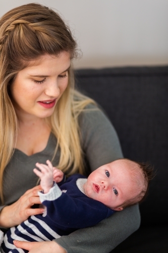 Little baby boy looking at camera from mothers arms - Australian Stock Image