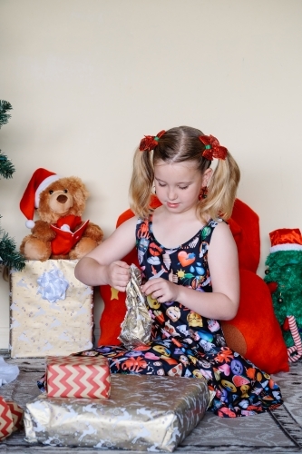 Little blonde girl unwrapping a Christmas present - Australian Stock Image