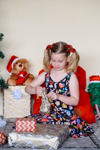 Little blonde girl unwrapping a Christmas present
