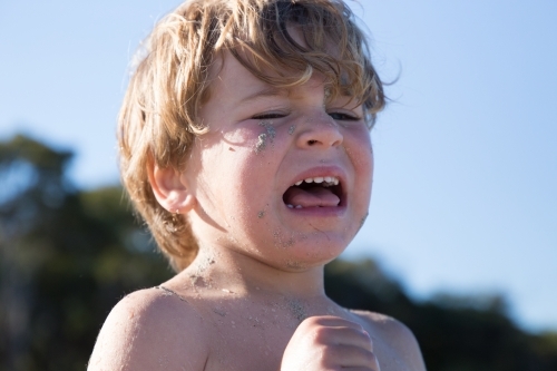 Little boy crying with sand on his face - Australian Stock Image