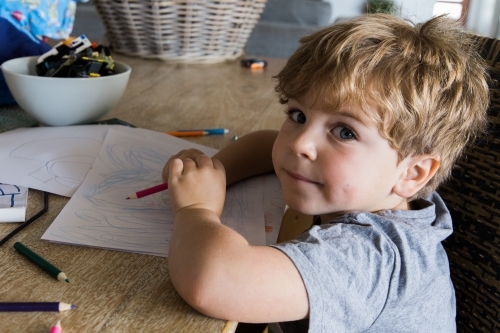 Little boy drawing with pencils at a table - Australian Stock Image