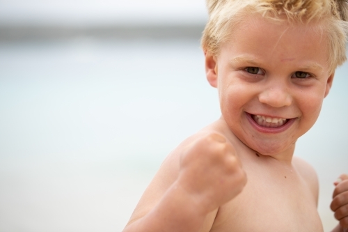 little boy flexing his muscles and clenching his fists - Australian Stock Image