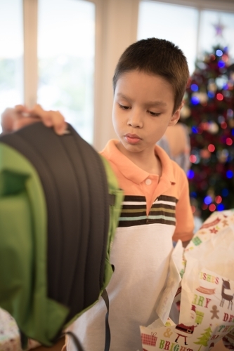 Little boy opening Christmas presents at home - Australian Stock Image