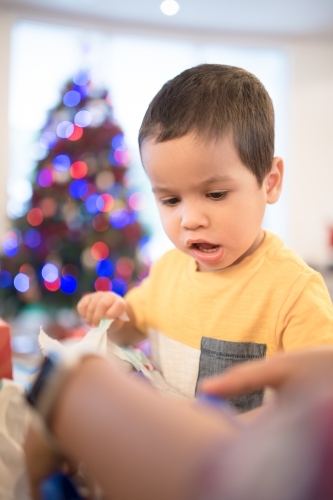 Little boy opening Christmas presents at home - Australian Stock Image