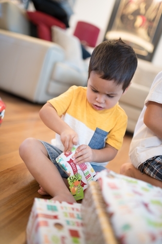 Little boy opening Christmas presents at home - Australian Stock Image