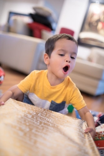 Little boy opening Christmas presents at home - Australian Stock Image