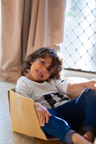 Little boy playing in a cardboard box - Australian Stock Image