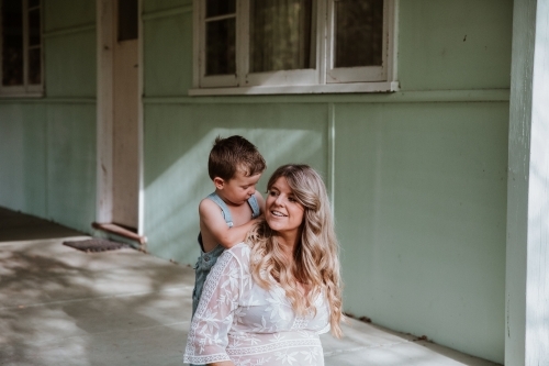 Little boy talking with his mother on the steps of front verandah - Australian Stock Image