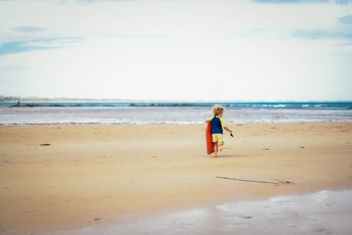 Little boy walking toward the water at the beach