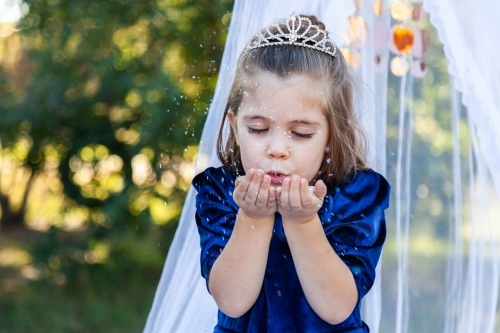 Little girl being a princess blowing sparkling glitter