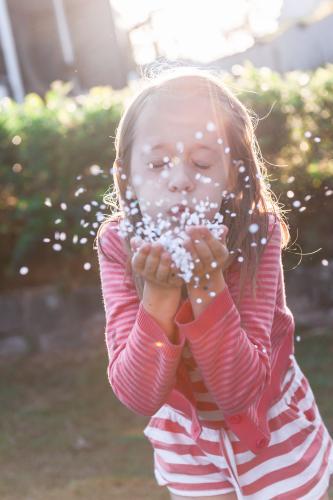 little girl blowing confetti from her hands - Australian Stock Image