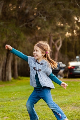 Little girl dancing and smiling outside - Australian Stock Image