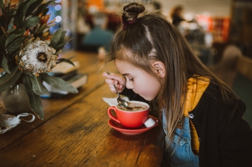 Little girl drinking a hot chocolate - Australian Stock Image