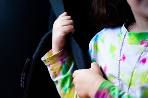 Little girl happily wearing seat belt in booster seat in car - Australian Stock Image