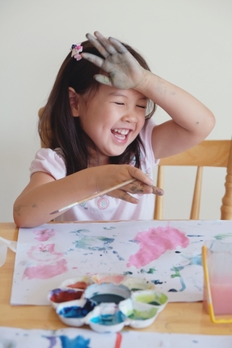 Little girl having fun painting at home - Australian Stock Image