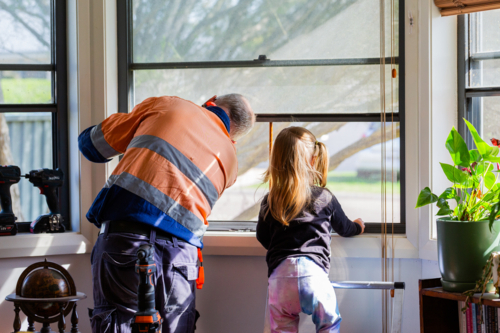Little girl helping grandfather fix the window at home - Australian Stock Image