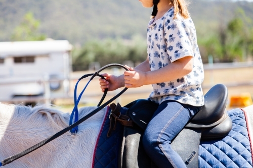 Little girl holding horses reins - Australian Stock Image