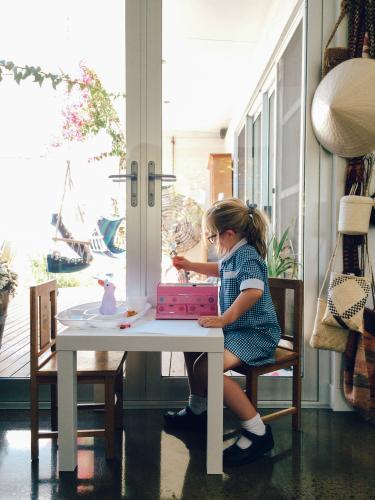 Little girl in school uniform doing homework after school - Australian Stock Image