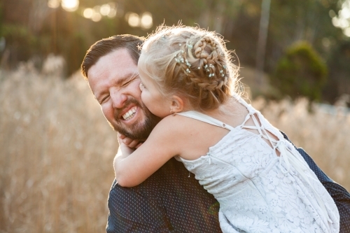 Little girl kissing her daddy on the cheek - Australian Stock Image