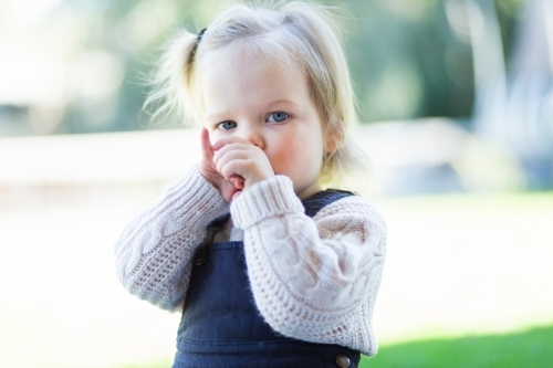 Little girl outside sucking her thumb - Australian Stock Image