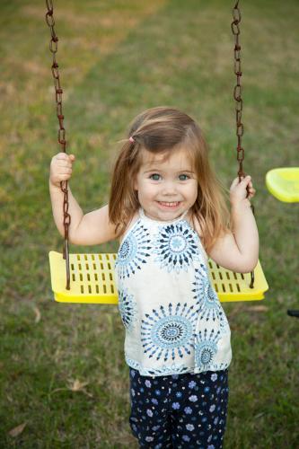Little girl playing on the swings in the backyard - Australian Stock Image