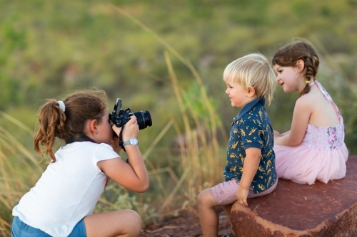 little girl playing photographer photographing other kids - Australian Stock Image