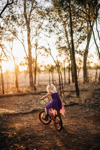 Little girl riding her bike at last light on farmland