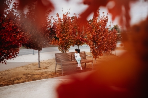 Little girl sitting amongst autumn trees