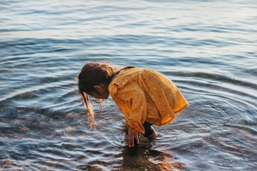 Little girl touching water in the sea