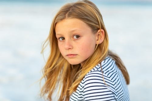 little girl wearing striped shirt looking over her shoulder - Australian Stock Image