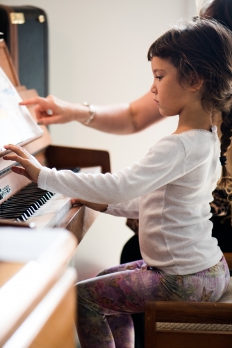 Little girl with Asian ethnicity learning to play the piano. - Australian Stock Image