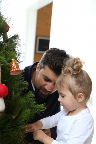 Little girl with dad decorating Christmas tree
