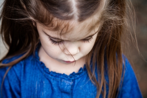 Little girl with pigtails looking down - Australian Stock Image