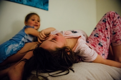Little girls playing on a bed