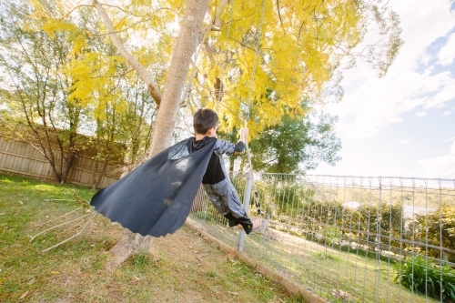 Little kid dressed up as Batman on a swing