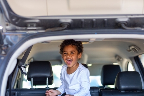 Little kid laughing in the back of a station wagon