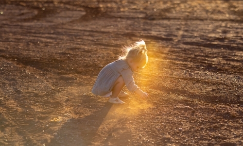 little kid playing in the dirt with backlight - Australian Stock Image