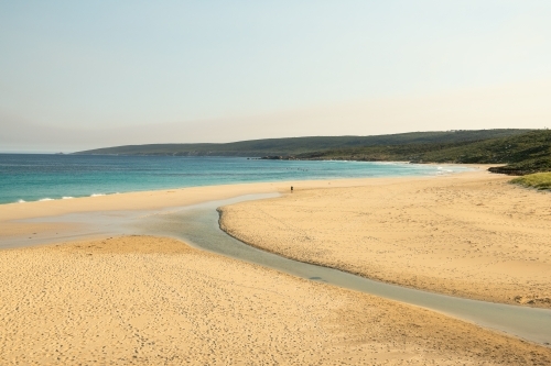 Loan hiker walking on beach with surfers in water - Australian Stock Image