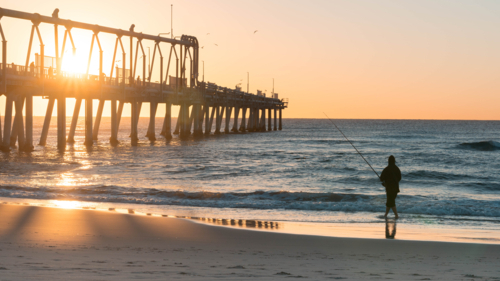Lone fisherman at southport spit at sunrise - Australian Stock Image